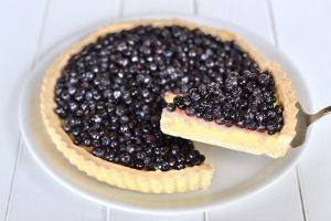 fetta di crostata con crema e mirtilli servita