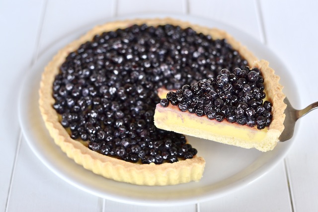 fetta di crostata con crema e mirtilli servita